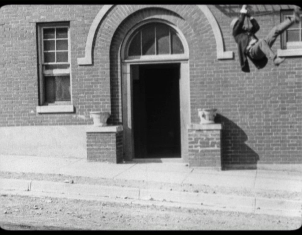 Tweedie-Dan escalando por una escalera un edificio para conseguir trabajo en el cine. YOU'RE NEXT. Marcel Perez. estrellamillansanjuan.es