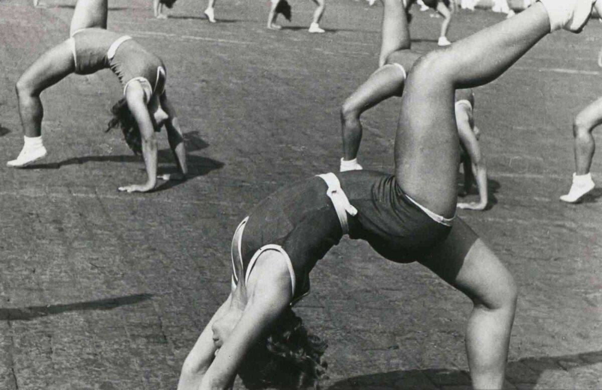 Fotografía de Aleksandr Ródchenko, perteneciente al constructivismo, el cual fotografió a mujeres haciendo actividades gimnásticas en composiciones poderosas, con ángulos vistosos cambiando las perspectivas para elevar la mujer fuerte y activa en acontecimientos deportivos que explotaban un cuerpo colectivo soviético a modo de propaganda. 