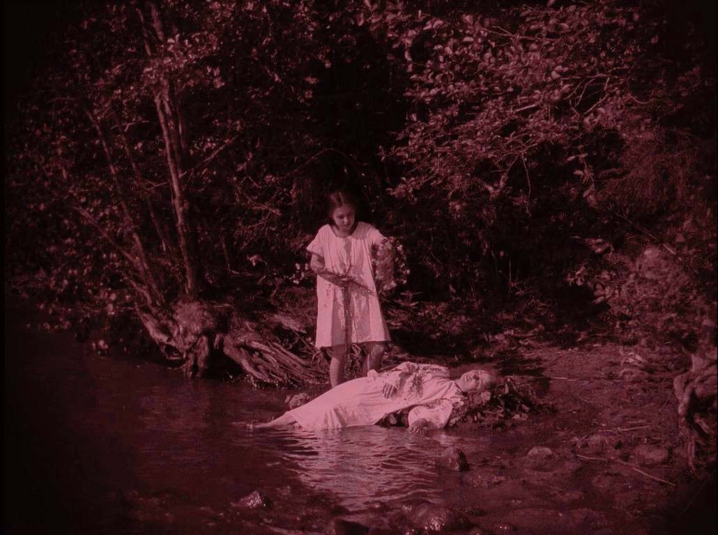 ANNA-LIISA (1922) de Teuvo Puro y Jussi Snellman 12 Escena onírica de la hermana encontrando a Anna-Liisa fallecida en el río. la corona con flores que ha recogido, Tintado rosa.