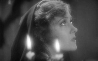 Kelly con velas rezando en convento primer plano. Queen Kelly
